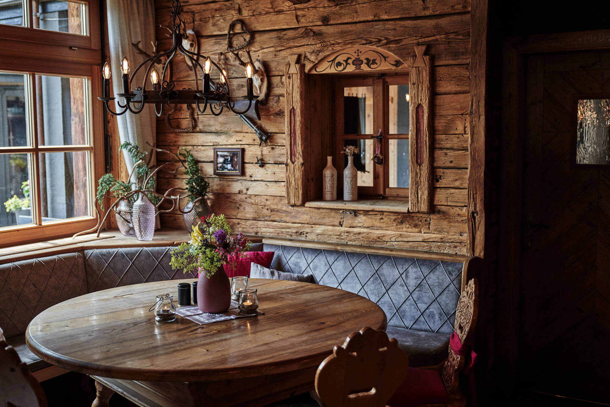 Gemütlicher Restaurantbereich mit Holzvertäfelung, runder Tisch und blühender Dekoration.