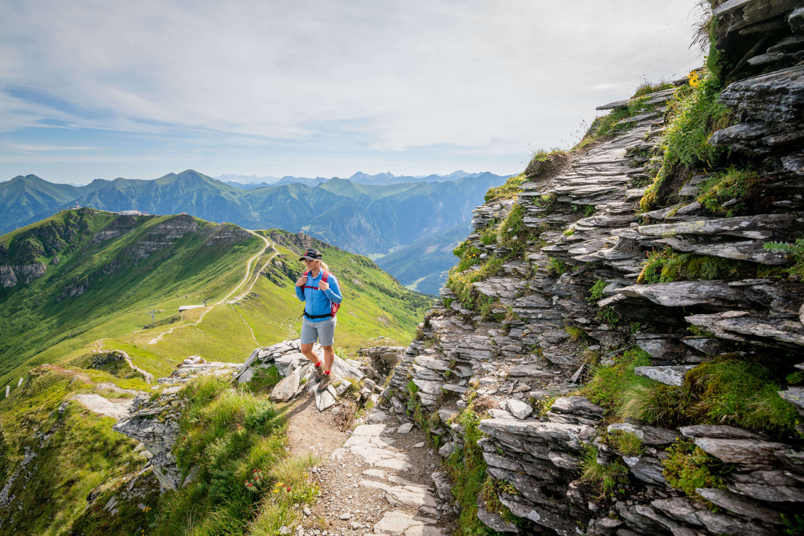 Wanderer auf einem Bergpfad mit grünen Wiesen und beeindruckender Bergkulisse in Bad Hofgastein.