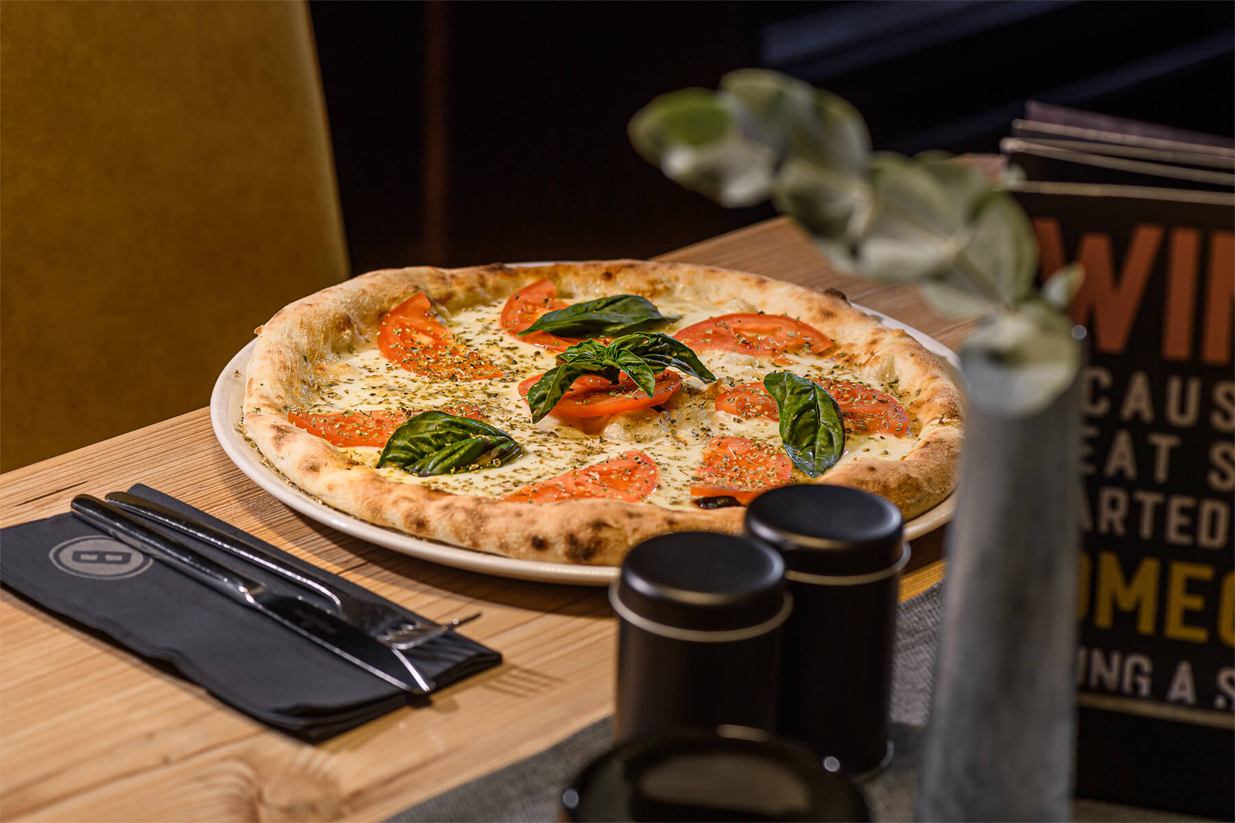 Gourmet-Pizza mit Tomaten und Basilikum auf einem Tisch im B&B Berglift in Bad Hofgastein.