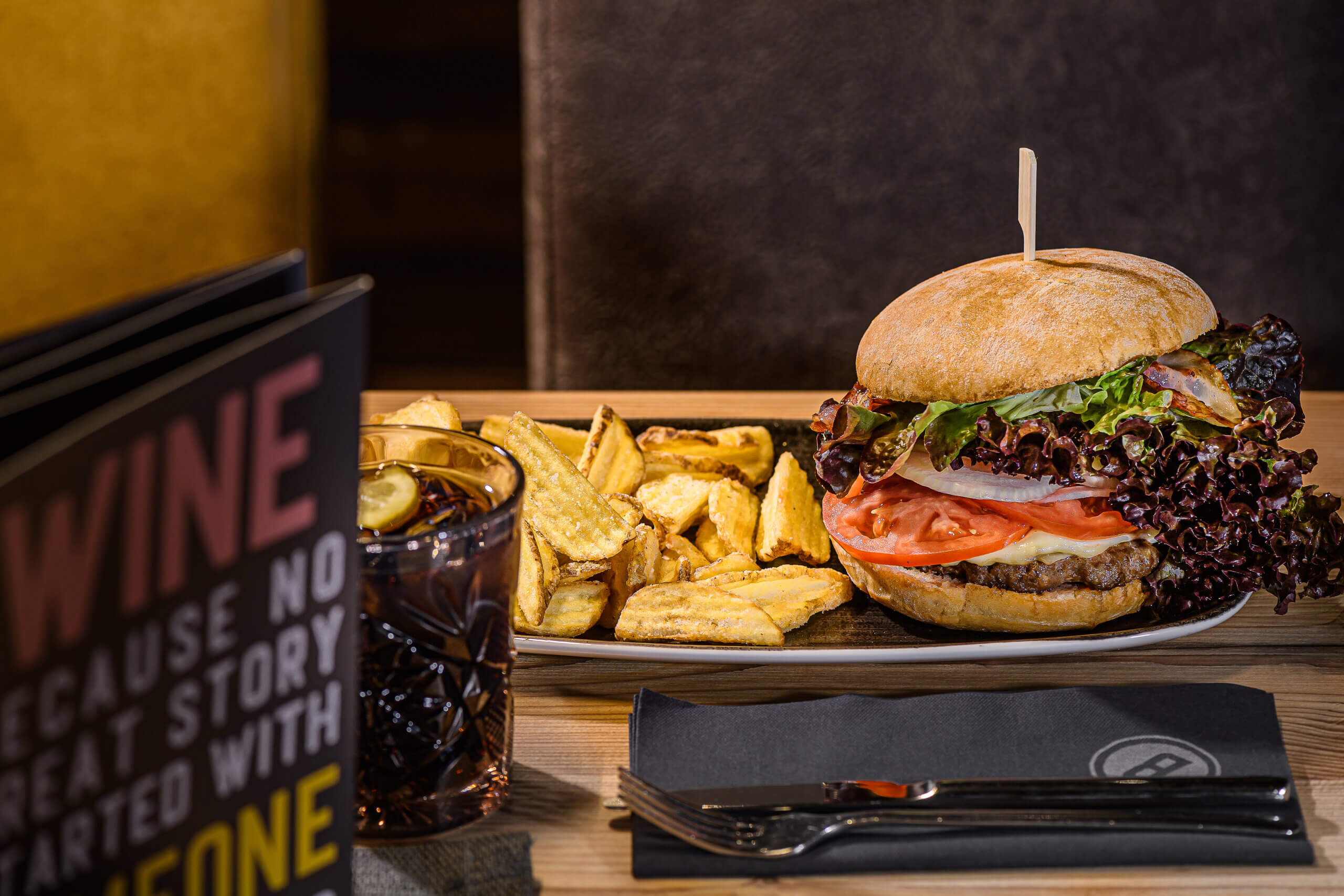 Saftiger Burger mit frischem Gemüse und knusprigen Pommes auf einem Teller im Restaurant.