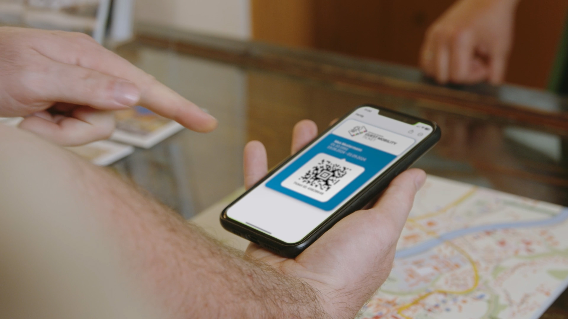 Hand hält Smartphone mit QR-Code vor Stadtplan in Bad Hofgastein