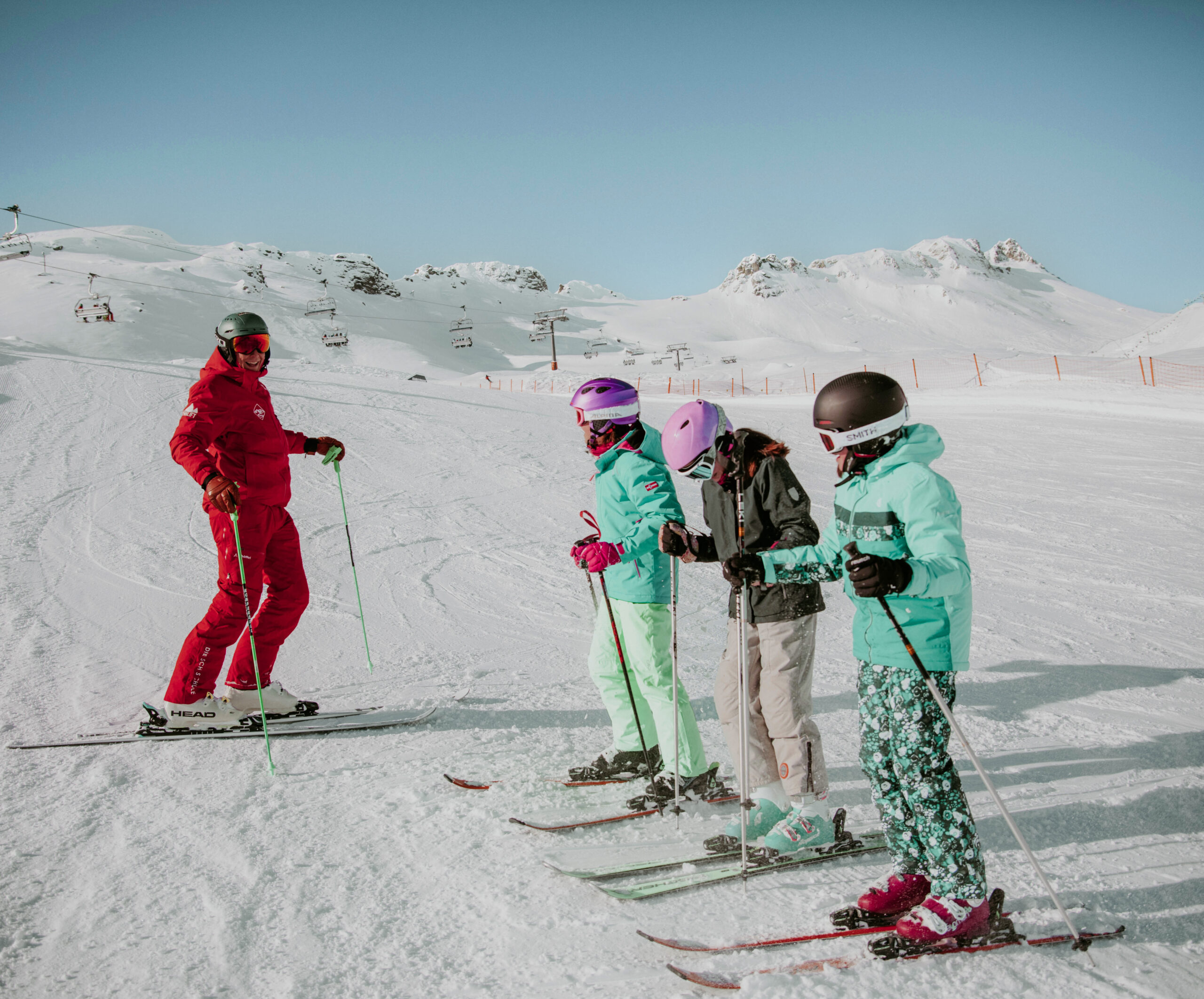 Skilehrer mit drei Kindern beim Skikurs im Schnee