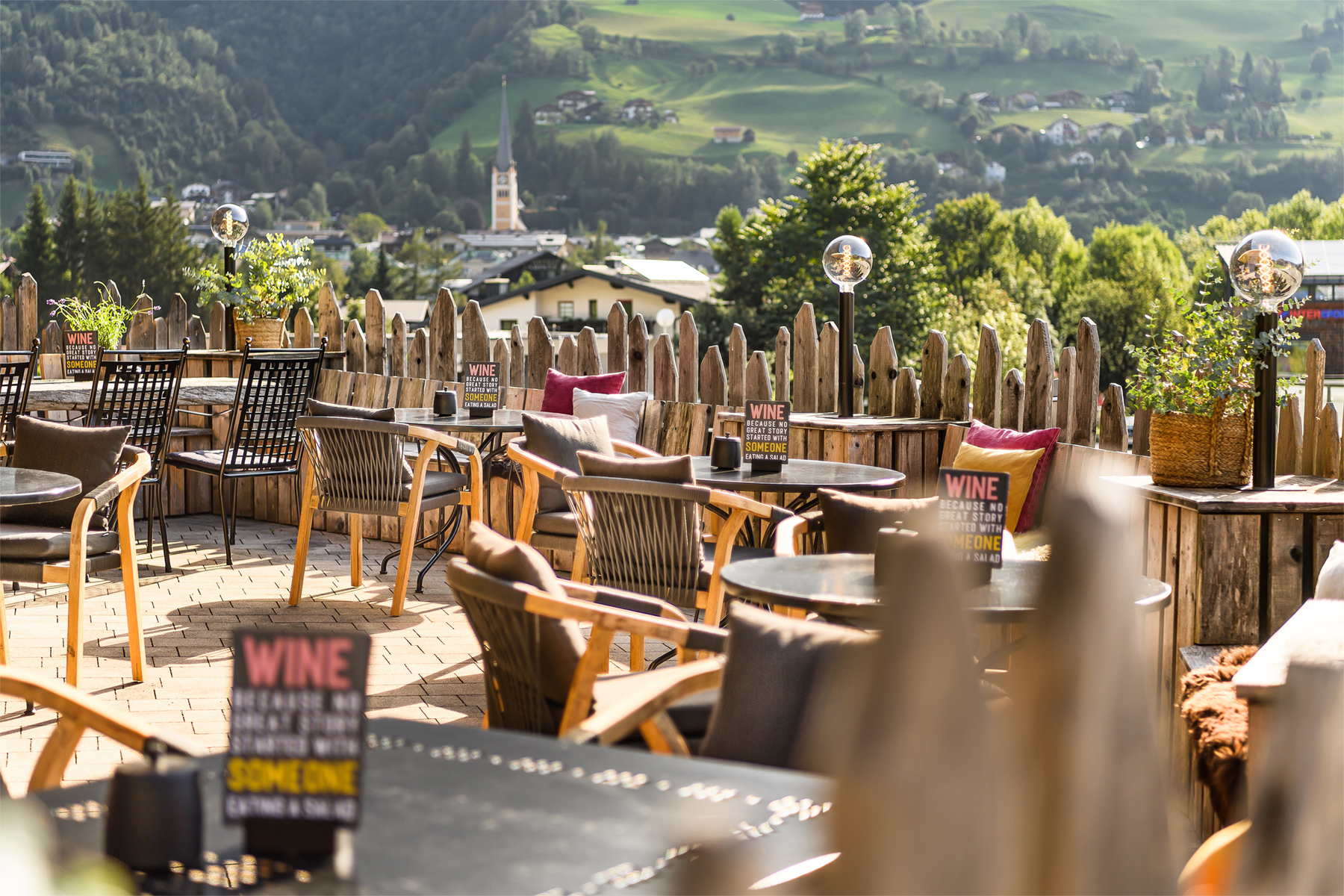 Gemütliche Sonnenterrasse mit Tischen und Blick auf Berge