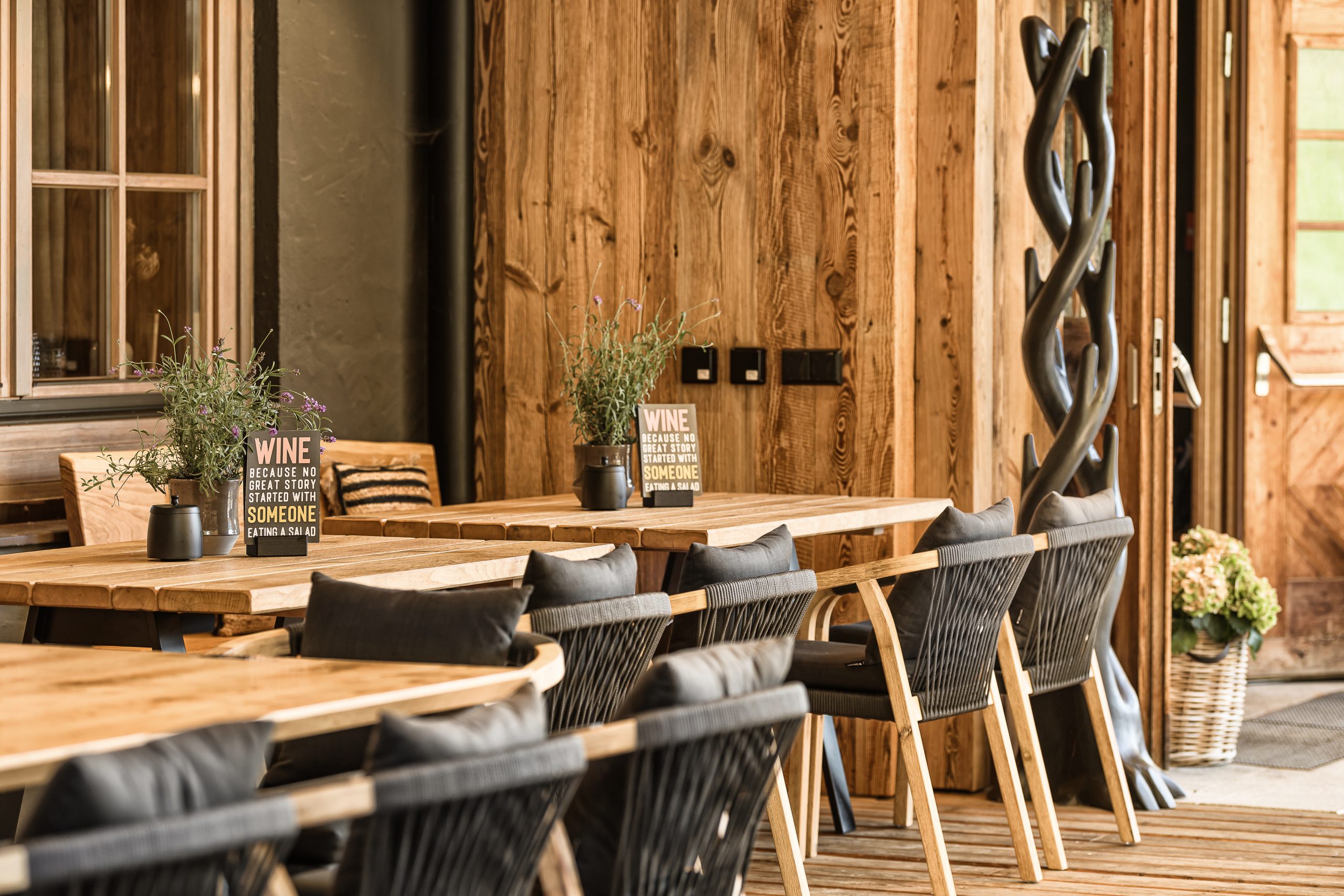 Holzterrasse mit Tischen, Stühlen und Pflanzen dekoriert