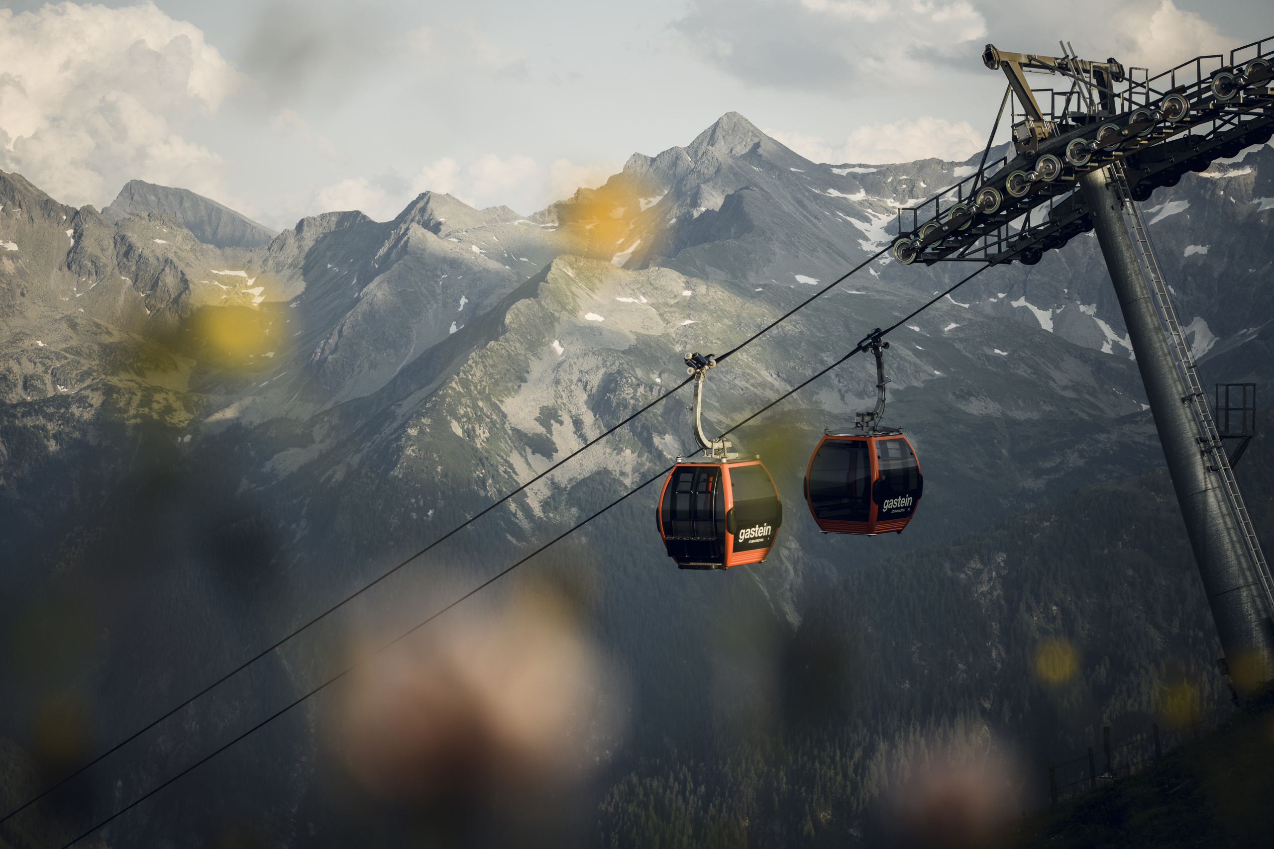 Zwei Gondeln einer Seilbahn vor schroffen, teils schneebedeckten Bergen