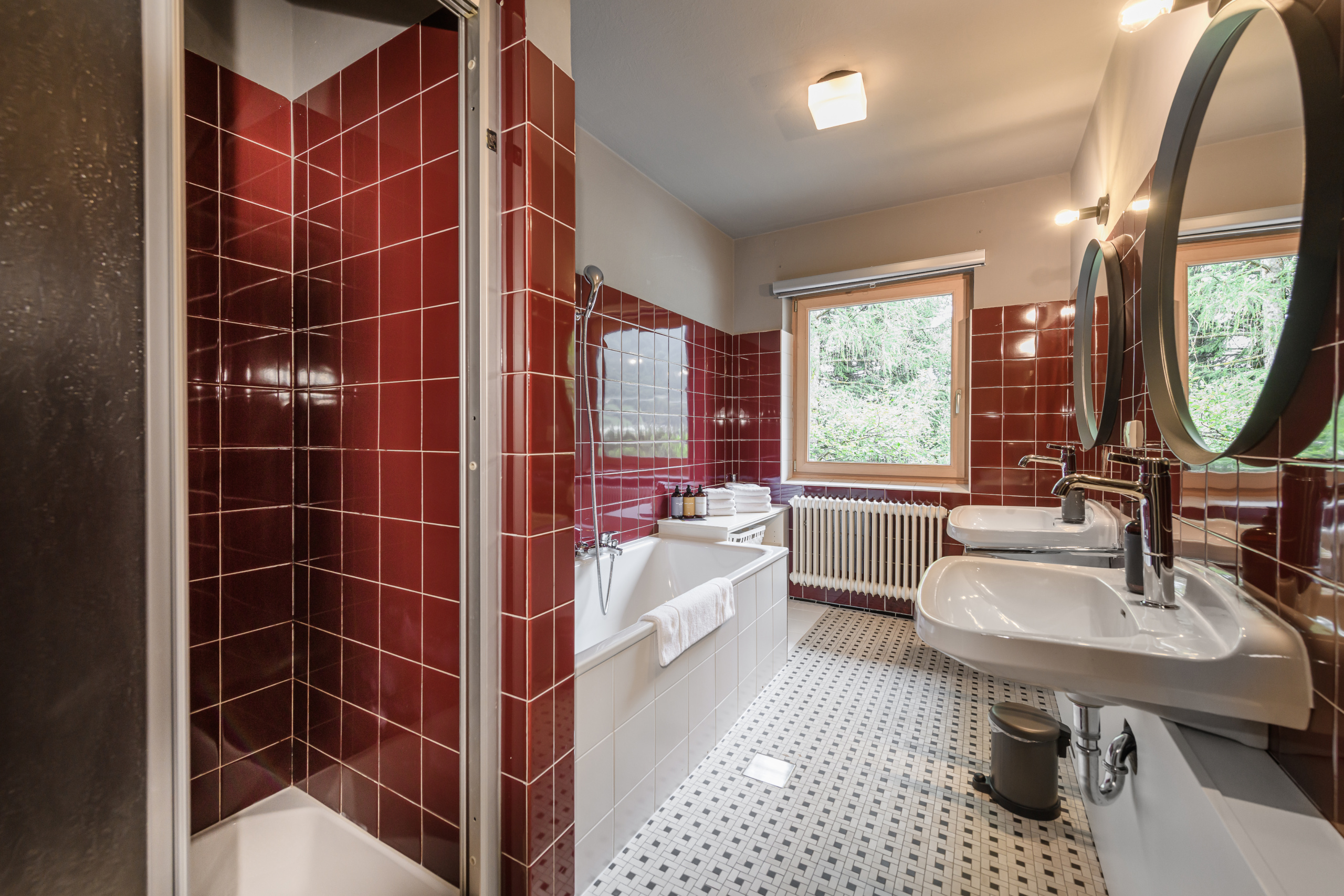 Badezimmer mit Dusche, Badewanne, Doppelwaschbecken und roten Fliesen