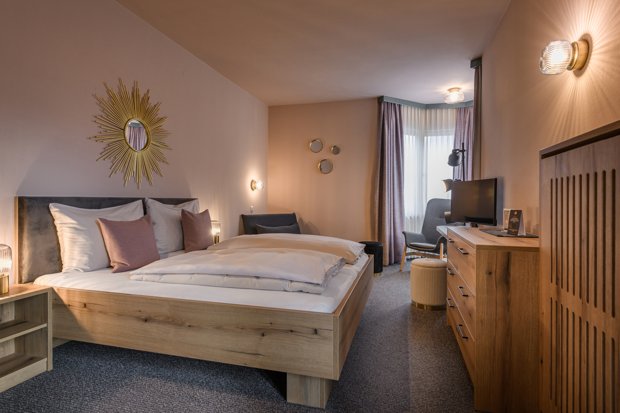 Doppelzimmer mit Holzbett, Sofa, Fernseher und Fenster mit Vorhängen
