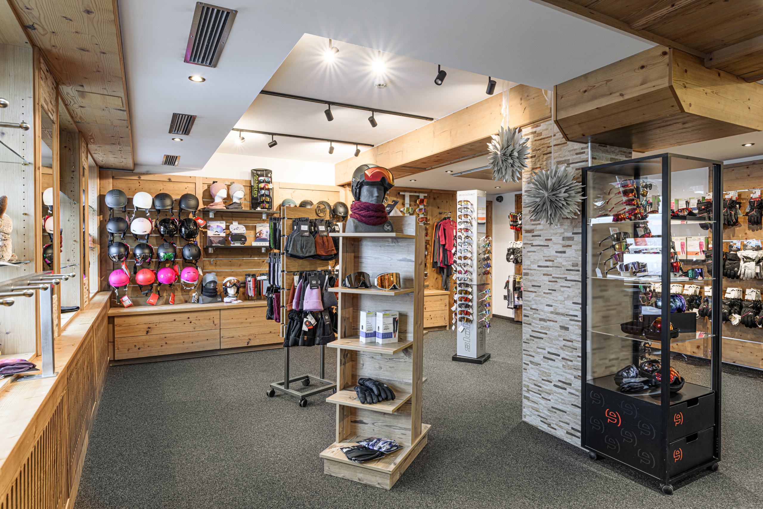 Heller Skiverleih mit Helmen, Skibrillen, Handschuhen und Winterbekleidung in Holzregalen