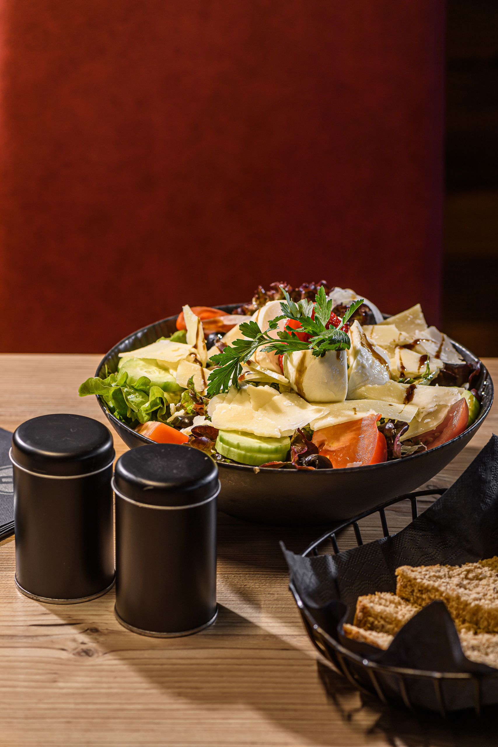 Große Schüssel gemischter Salat mit Käse, Tomaten, Gurke und Kräutern auf Holztisch