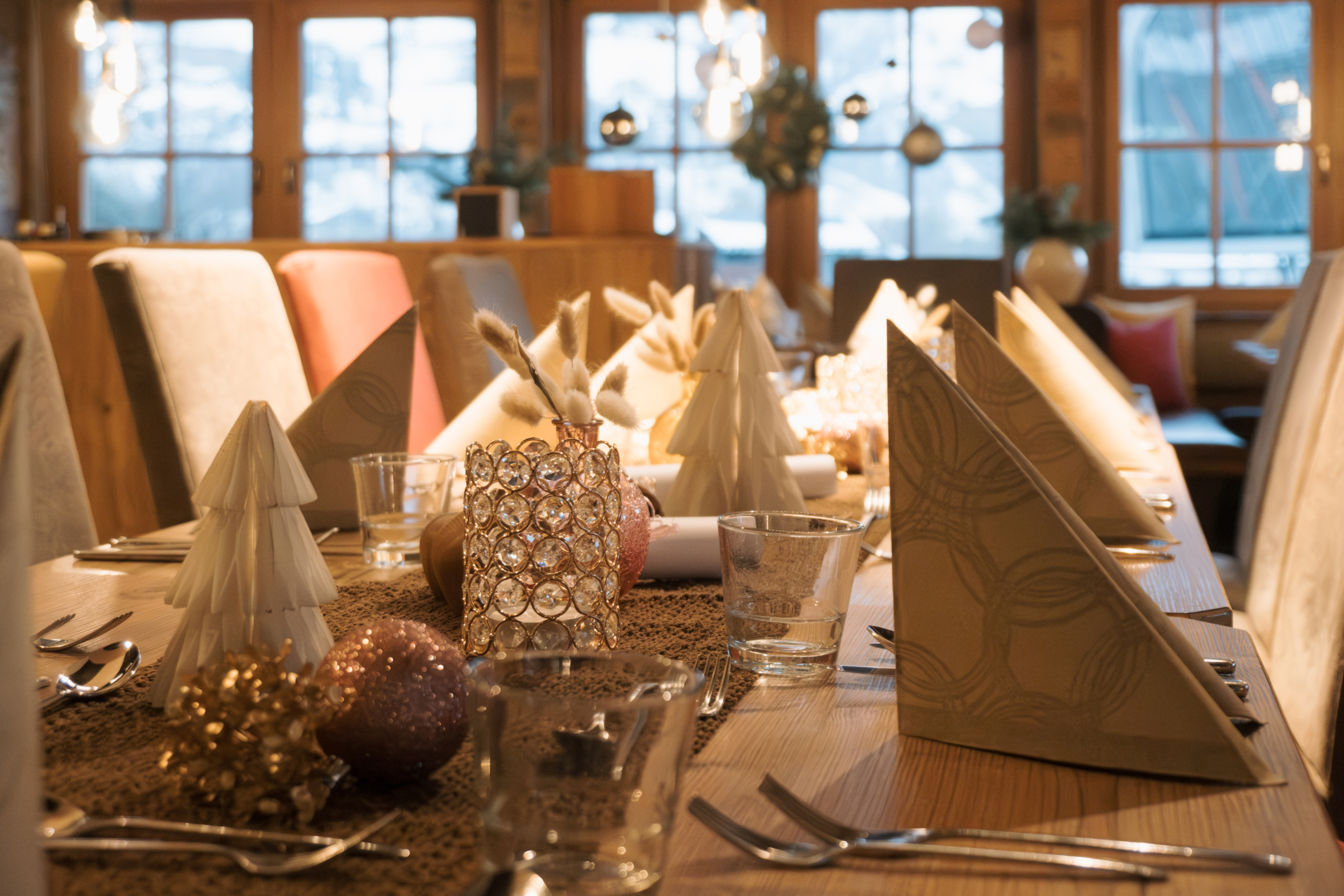 Festlich gedeckter langer Tisch mit Servietten, Gläsern und Weihnachtsdekoration in einem holzvertäfelten Restaurant