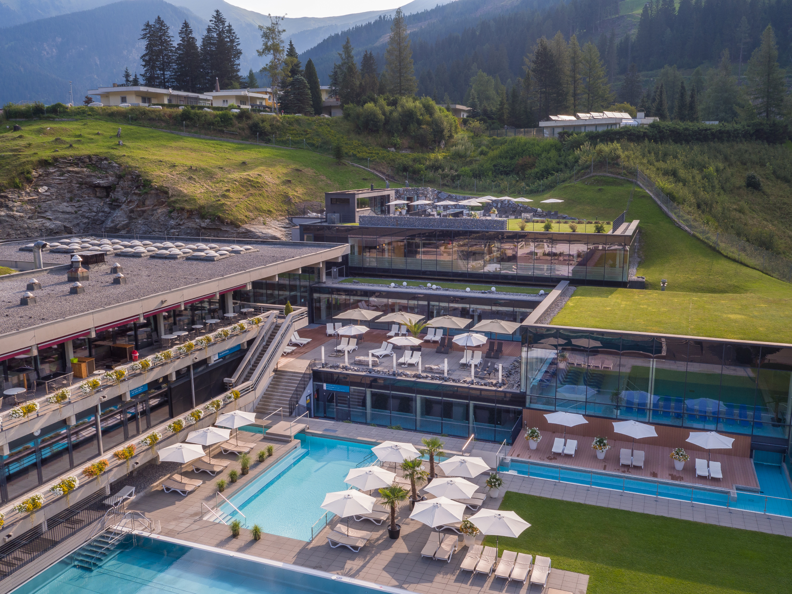 Außenbecken und Sonnenterrassen der Felsentherme Bad Gastein vor bewaldeten Bergen